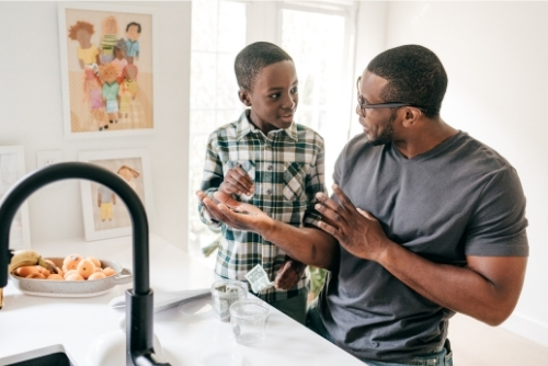 Father and son counting money in kitchen