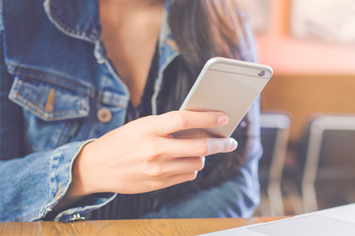 Woman sitting at desk scrolling on phone